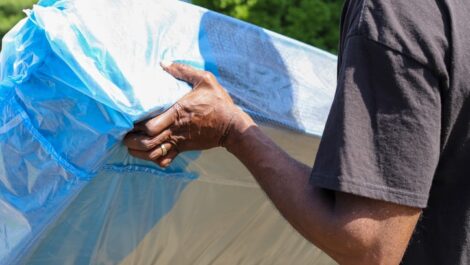 A man in a black shirt lifts a mattress.