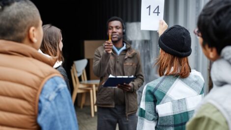 Young woman holding a number card and bidding on a container at an outdoor auction.